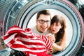 Funny couple loading clothes to washing machine