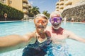 Funny couple of mature people take selfie picutre while enojy and have fun at the pool in residence - elderly retired happy Royalty Free Stock Photo