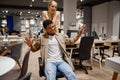 Funny couple riding office chair at shop Royalty Free Stock Photo