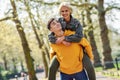 Funny couple in a urban park. Boyfriend carrying his girlfriend on piggyback. Royalty Free Stock Photo