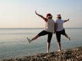 Funny Couple of women in santa claus hats on the sea beach, silhouette women as Santa hats hold hands and raise arms and legs. two Royalty Free Stock Photo