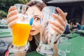 Crazy asian girl with two Beers on the terrace of the beer restaurant in Germany. The concept of a hangover and Royalty Free Stock Photo