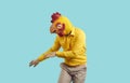 Funny crazy man with chicken head dancing isolated on pastel light blue background.