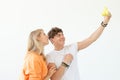 Funny crazy young couple blonde girl and a hipster guy taking a selfie on a vintage yellow film camera posing on a white Royalty Free Stock Photo