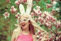 Funny crazy young woman in blossoming magnolia flower, spring. Happy easter. Sexy woman in bunny ears. Spring, nature