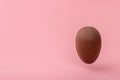 Funny creative concept of flying chocolate egg over pink background, copy space Royalty Free Stock Photo