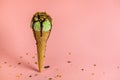 funny creative concept with unstable pistachio ice cream cone with chocolate sauce and strewed nuts on pink Royalty Free Stock Photo