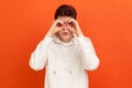 Funny curious young man in casual white sweatshirt looking far away through binoculars gesture, spying with open mouth, shocking