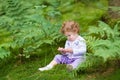 Funny curly baby girl eating wild raspberries in forest Royalty Free Stock Photo