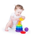 Funny curly baby girl playing with a colorful pyramid
