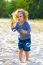 Vertical photo of a little curly girl with soap bubbles on the beach Royalty Free Stock Photo