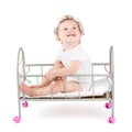 Funny curly baby paying in a doll bed Royalty Free Stock Photo