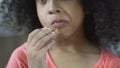 Funny curly-haired girl eating cookie at home, close-up of female child snacking