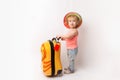 Funny curly little baby girl in a hat, T-shirt and jeans with a yellow suitcase is smiling on a white background waiting for an Royalty Free Stock Photo