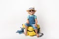Funny curly little baby girl in a hat, T-shirt and jeans with a yellow suitcase is smiling on white background waiting for an Royalty Free Stock Photo