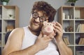 Funny curly man in eyeglasses tenderly hugging his piggy bank and smiling happily Royalty Free Stock Photo