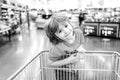 Funny customer boy child holdind trolley, shopping at supermarket, grocery store. Royalty Free Stock Photo