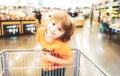 Funny customer boy child holdind trolley, shopping at supermarket, grocery store. Royalty Free Stock Photo