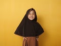 Funny cute Asian muslim little girl wearing hijab looked angry and upset, looking at camera, against yellow Royalty Free Stock Photo