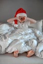 Funny cute boy waking up and rubing your eyes in a Santa hat. Happy holidays. Christmas morning concept