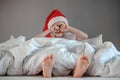 Funny cute boy waking up and rubing your eyes in a Santa hat. Happy holidays. Christmas morning concept