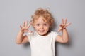 Funny cute charming little toddler girl baby in white T-shirt isolated over gray background raised her arms pretending frighting Royalty Free Stock Photo