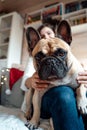 Funny cute dog,french bulldog lying on the lap of owner, young girl. Woman sitting on couch with pet. Happy family celebration and Royalty Free Stock Photo