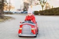 Funny cute girl driving a big toy red fire truck. A little girl drives a children`s car on a city street. A cute girl is enjoying