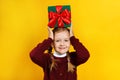 Funny cute happy little girl holds a box with a gift on her head. Royalty Free Stock Photo