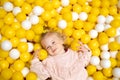 Funny cute little caucaisian blonde baby girl,toddler, smiling kid having fun in ball pool,playing with yellow white Royalty Free Stock Photo