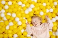 Funny cute little caucaisian blonde baby girl,toddler, smiling kid having fun in ball pool,playing with yellow white Royalty Free Stock Photo