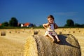 Funny cute little girl posing on the haystack in summer field Royalty Free Stock Photo