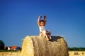 Funny cute little girl posing on the haystack in summer field Royalty Free Stock Photo