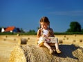 Funny cute little girl posing on the haystack in summer field Royalty Free Stock Photo