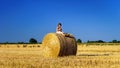 Funny cute little girl posing on the haystack in summer field Royalty Free Stock Photo