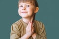 Funny Cute little girl praying on a blue background with a place to copy. The blonde, happy, smiling little girl folded her hands