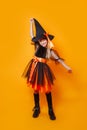 Funny little girl in witch Halloween costume on orange background Royalty Free Stock Photo