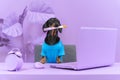 Funny dachshund in blue t-shirt and with brush in its mouth is sitting at table in room completely painted in lilac