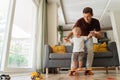 Funny daddy playing active games with little son at home, wheeling penny board in living-room