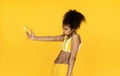 Funny african teen girl hold banana gun shooting isolated on yellow background Royalty Free Stock Photo