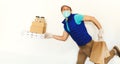Funny delivery man in uniform face mask gloves carrying many cardboard boxes, running and hurrying to deliver takeout