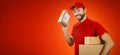 Funny delivery service man with box in hand on red background with copy space