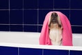 FUNNY DOG BATHING. LABRADOR RETRIEVER COVERED AND WRAPPED WITH A PINK TOWEL ON A BLUE BATHTUB