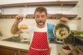 Funny portrait of messy and disaster home cook man holding corn bag and pot with burnt popcorn in failure cooking attempt