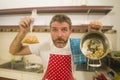 funny portrait of messy and disaster home cook man holding corn bag and pot with burnt popcorn in failure cooking attempt