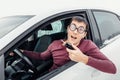 Driver in eye glasses holding the car key and smiling to the camera. Concept of a newbie driver and insurance Royalty Free Stock Photo