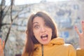 Funny emotional female portrait of young brunette in bright yellow jacket looking at the camera with unbelievable shock