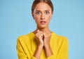 Funny emotional girl in a yellow sweater with a surprised scared face on blue background