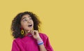 Funny ethnic preteen girl with omg facial expression looks at copy space on yellow background.