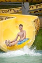 Funny excited child enjoying summer vacation in water park riding yellow float laughing